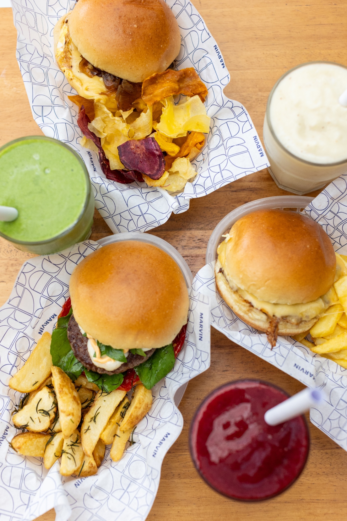 Composição com hambúrgueres artesanais Marvin, batatas, chips e sucos naturais
